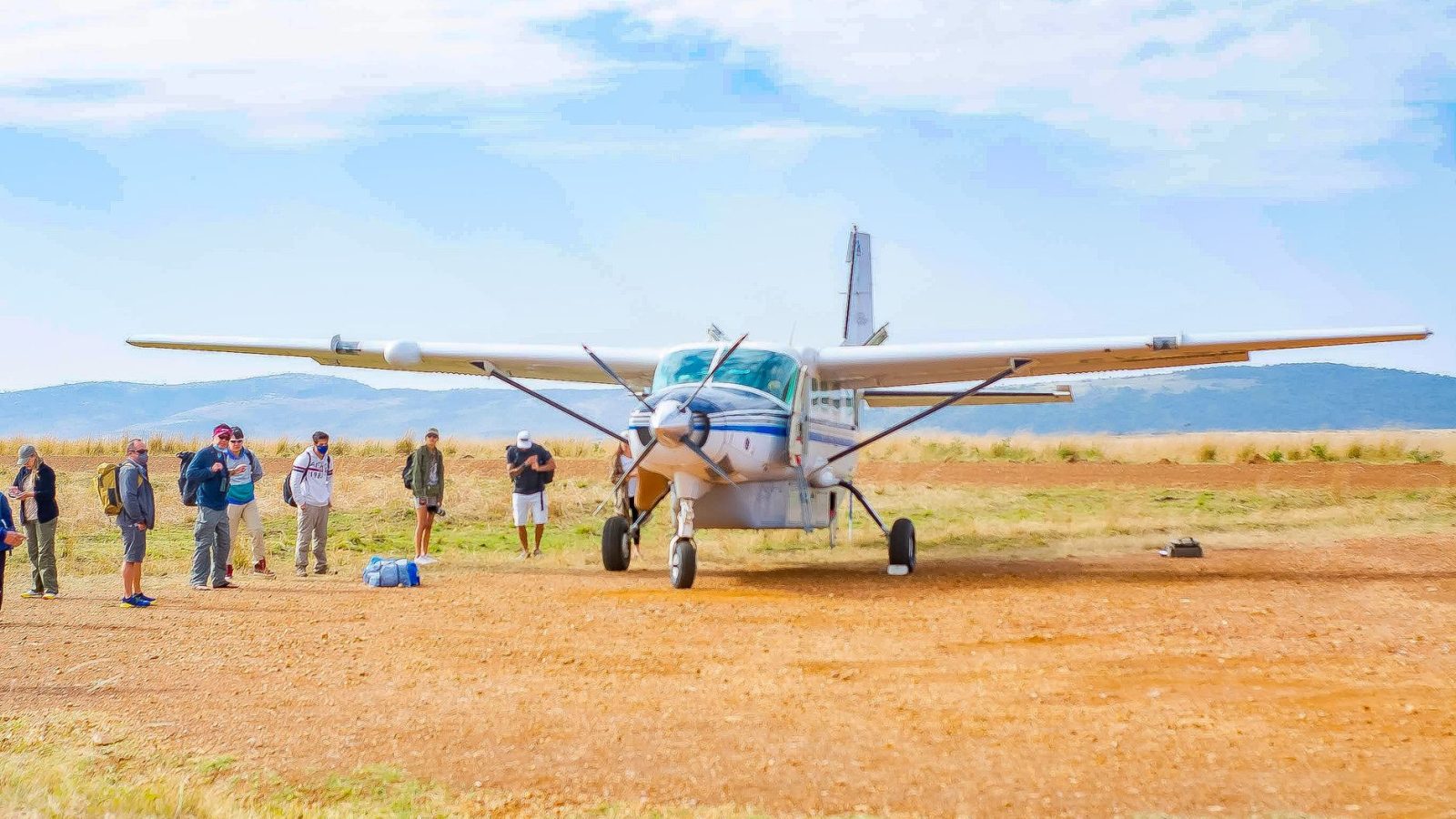 Voyageurs près d’un petit avion de brousse sur une piste en terre
